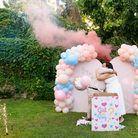 Parents-to-be hugging at a gender reveal