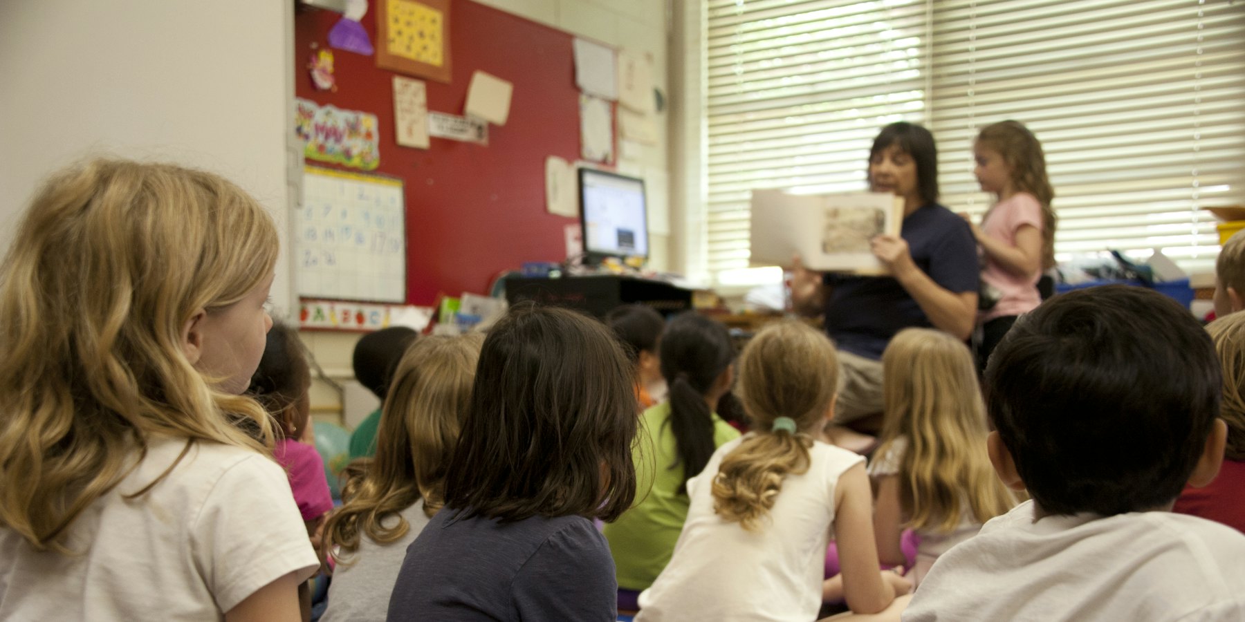 A class of children listening to their teacher read a story